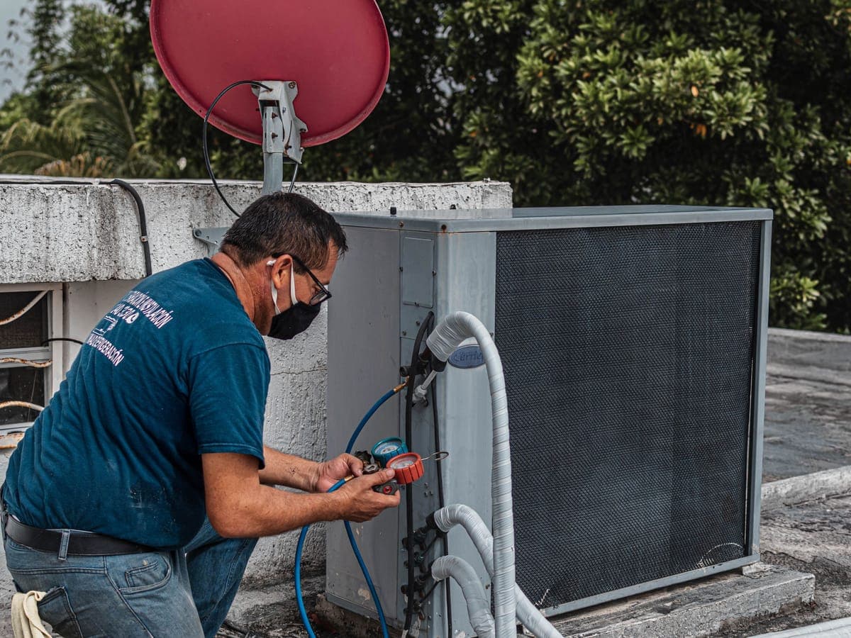 Technician checking an outdoor AC unit with a multimeter
